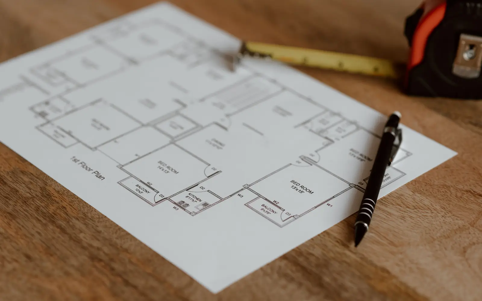 A printed floor plan with a pen and tape measure on a timber surface