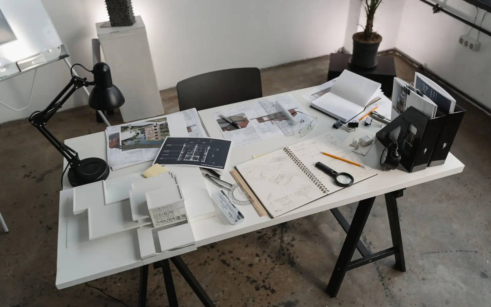 A work table covered with floor plans, drawings and drafting tools