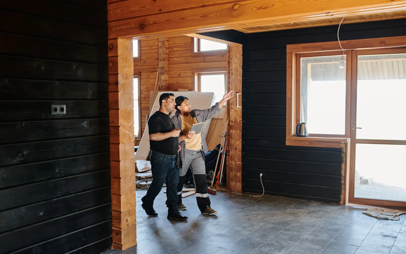 Two people walking through a timber-framed interior under construction, one pointing out details